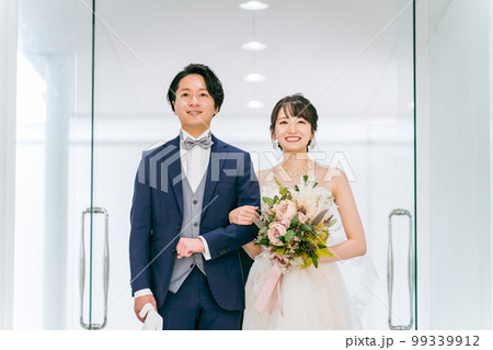 結婚式でチャペル・結婚式場・バージンロードにブーケを持って入場する新郎新婦 99339912