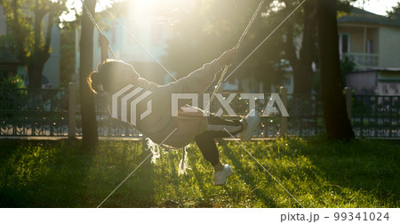 pretty woman rides on a swing near her house pretty woman rides on a swing near her house 99341024