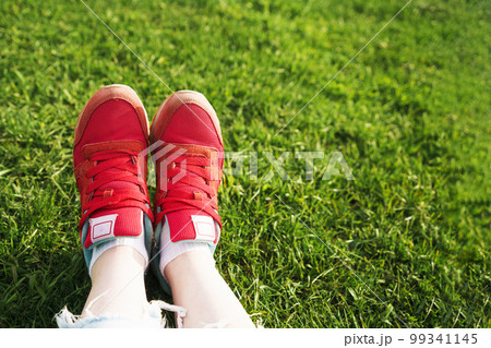 female legs in sneakers on a background of green grass female legs in sneakers on a background of green grass 99341145