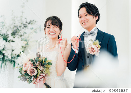 結婚式場で赤い糸で結ばれる新郎新婦（ブライダル・ウェディング） 99341687