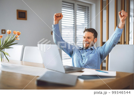 Man watching a football game on laptop, thrilled with his team winning 99346544
