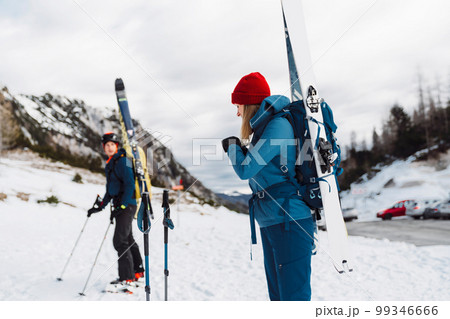 Couple of ski tourers carrying their skies tied up on a backpack Couple of ski tourers carrying their skies tied up on a backpack 99346666