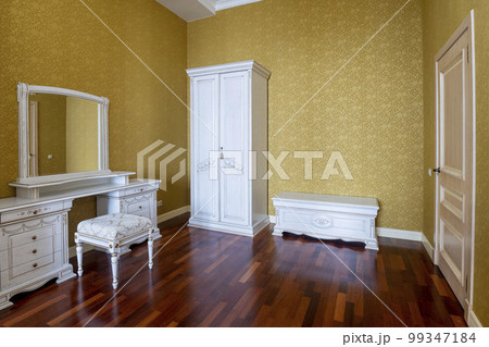 White wooden furniture in the bedroom with yellow wallpaper and brown floor 99347184