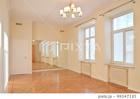 A hall in an empty bright apartment with large windows and a shiny floor 99347185