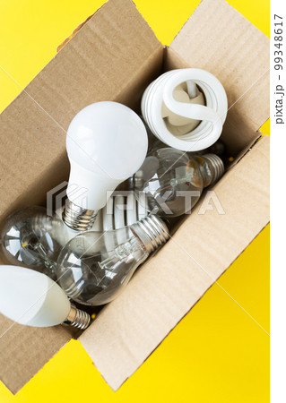 A set of different types of LED and incandescent lamps in a craft box on a yellow background. 99348617