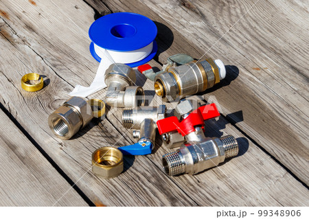 Various plumbing spare parts and sealing tape on rustic wooden background 99348906