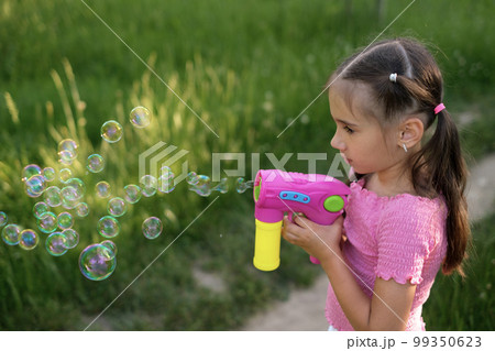 A child blows soap bubbles with a gun. 99350623