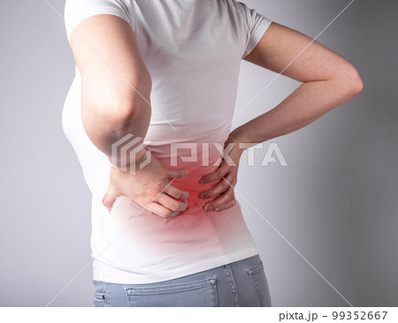 Woman suffering from backache. Hands holding lower back with red spot closeup. Health and medicine concept. Sedentary lifestyle, injury during sports 99352667