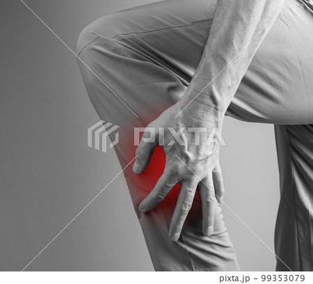 Shin splints. Man holding painful leg with red spot closeup. Overuse injury, cramp, medial tibial stress syndrome. Health care, orthopedic problems and treatment concept. Black and white 99353079