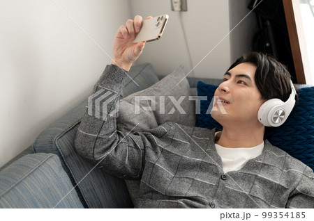 ソファーでスマートフォンを見る男性 99354185
