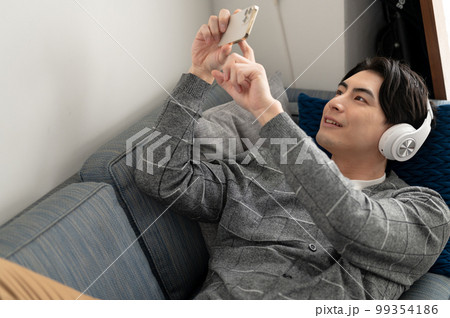 ソファーでスマートフォンを見る男性 99354186