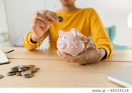 Saving money investment for future. African american girl holding pink piggy bank and putting money coin. Saving investment budget business wealth retirement financial money banking concept 99354518