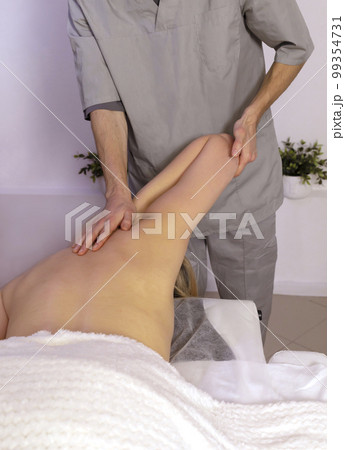 Male therapist, masseur lifts bent elbow of white woman, client up during professional therapeutic massage in spa salon. Fascia stretch. Mental,health sustainability. Relaxation, healthcare. Vertical Male therapist, masseur lifts bent elbow of white woman, client up during professional therapeutic massage in spa salon. Fascia stretch. Mental,health sustainability. Relaxation, healthcare. Vertical 99354731