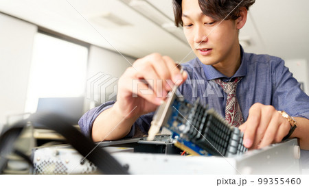 オフィスにてPCをメンテナンスする男性スタッフ　セッティング　キッティング　ビジネスイメージ 99355460