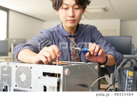 オフィスにてPCをメンテナンスする男性スタッフ　セッティング　キッティング　ビジネスイメージ 99355464
