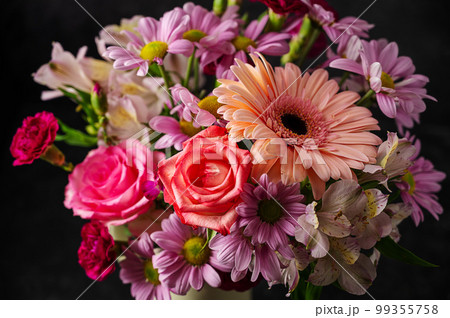 Beautiful fresh spring flowers. Pink bouquet of flowers in vase, on black background. 99355758