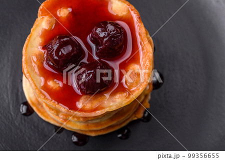 Delicious fresh pancakes with berry jam on a black ceramic plate Delicious fresh pancakes with berry jam on a black ceramic plate 99356655