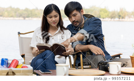 Couple camping for the weekend in the woods near the river, Leisure and relaxation activities in the midst of nature, Man taking photo of woman to capture memories, Couple outdoor leisure activities. 99357211