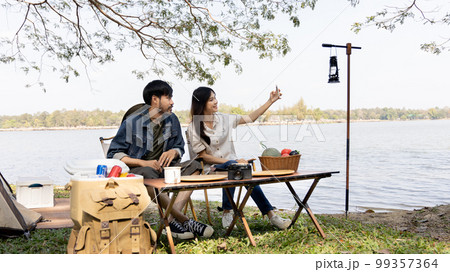 Camping for the weekend in the woods near the river, Relaxation activities for young couples, Woman using mobile phone to take a selfie with her boyfriend, Young couple outdoor leisure activities. Camping for the weekend in the woods near the river, Relaxation activities for young couples, Woman using mobile phone to take a selfie with her boyfriend, Young couple outdoor leisure activities. 99357364