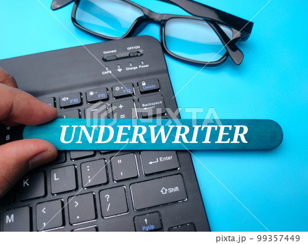 Keyboard and glasses with the word UNDERWRITER on a blue background. Keyboard and glasses with the word UNDERWRITER on a blue background. 99357449
