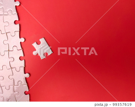 Unfinished white jigsaw puzzle pieces on red background Unfinished white jigsaw puzzle pieces on red background 99357619