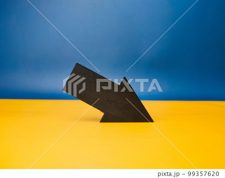 Wooden black arrow with copy space on a yellow and blue background. Wooden black arrow with copy space on a yellow and blue background. 99357620