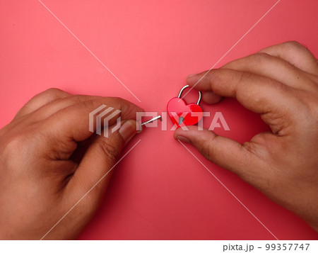 Top view someone hand holding key and love padlock on a red background. Loving and valentine concept. Top view someone hand holding key and love padlock on a red background. Loving and valentine concept. 99357747