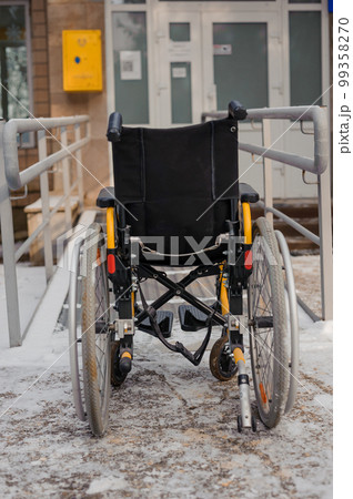 Empty wheelchair in the hospital on the ramp. Wheelchair close-up. Children's wheelchair Empty wheelchair in the hospital on the ramp. Wheelchair close-up. Children's wheelchair 99358270