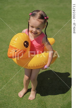Funny wet girl came out of the pool with an inflatable circle in the shape of a duck. The child froze in cold water and chills , went out to bask in the sun 99358711