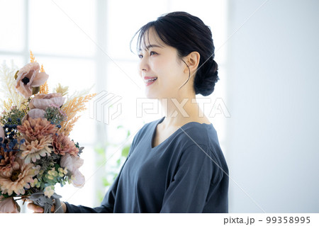 花束を持つグレーのワンピースの女性 99358995