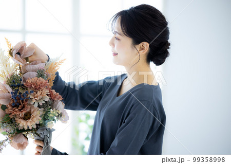 花束を持つグレーのワンピースの女性 99358998