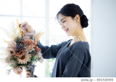 花束を持つグレーのワンピースの女性 99358999