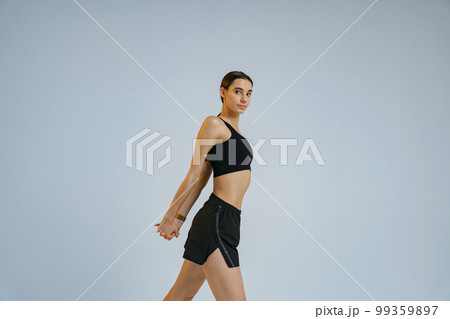 Close up of sporty woman doing warm-up before training session in gym on studio background 99359897