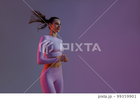 Sporty determined woman running during cardio workout over studio background 99359901