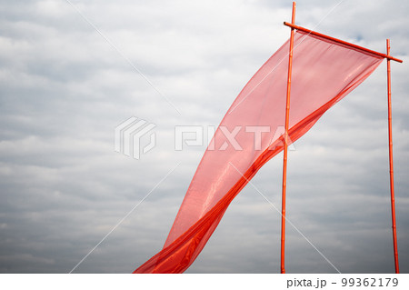 Red silk fabric develops against the background of white clouds Red silk fabric develops against the background of white clouds 99362179