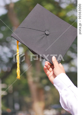 Student hold hats in hand during commencement success on yellow background Student hold hats in hand during commencement success on yellow background 99363000
