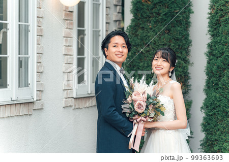 結婚式で結婚式場の庭でブーケを持つ新郎新婦（ガーデンウェディング） 99363693