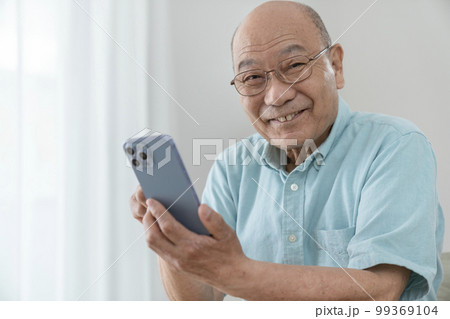 スマートフォンを持った70代後半の男性　カメラ目線　ポートレート 99369104