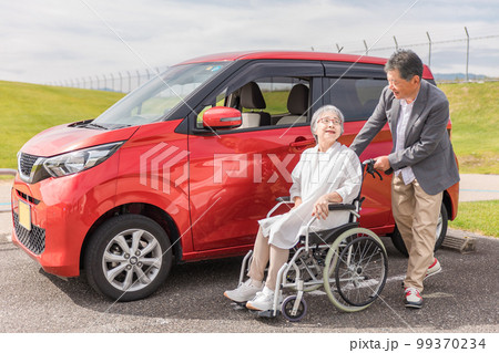 自動車の前にいる車椅子の高齢者女性と男性（シニア・夫婦・男女） 99370234