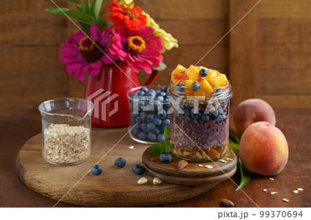 Homemade granola, muesli with blueberry and yogurt in glasses on rustic wooden background. Healthy breakfast. 99370694