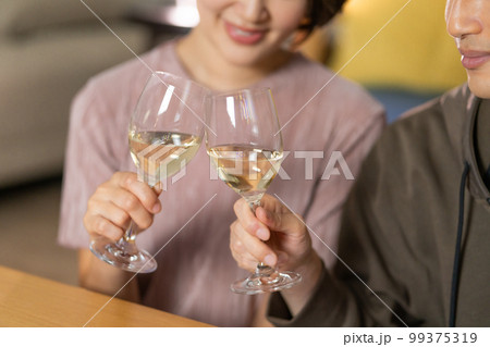 夜 リビングで白ワインで乾杯する若い夫婦 夜 リビングで白ワインで乾杯する若い夫婦 99375319