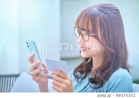 カードを使ってネットショッピングする若い女性 カードを使ってネットショッピングする若い女性 99375352