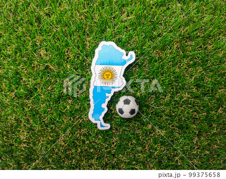 A ball and Argentina flag sticker is on a green field. 99375658