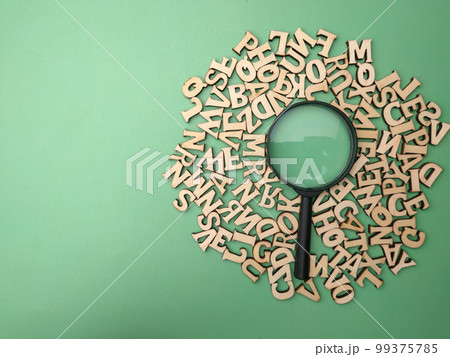 Wooden word and magnifying glass on a green background. Business concept. Wooden word and magnifying glass on a green background. Business concept. 99375785