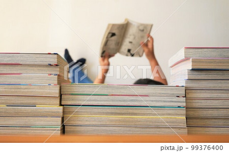 寝転んで本を読む人物 99376400