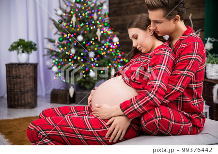 Hugging couple expecting a baby seen in profile 99376442