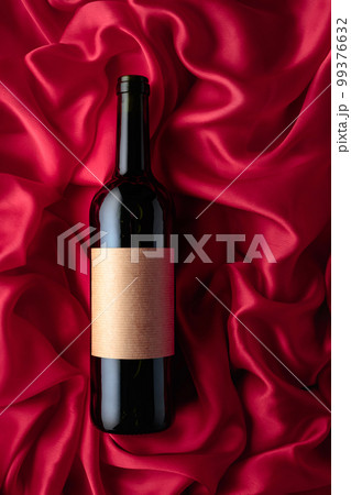 Bottle of red wine with an empty label on a satin background. 99376632