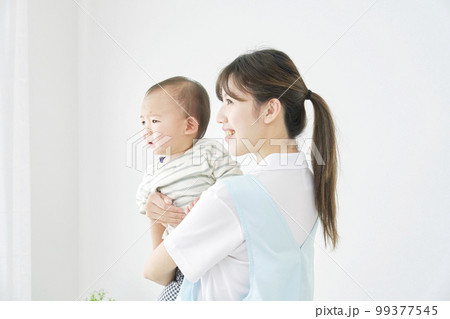 赤ちゃんを抱っこする保育士 99377545