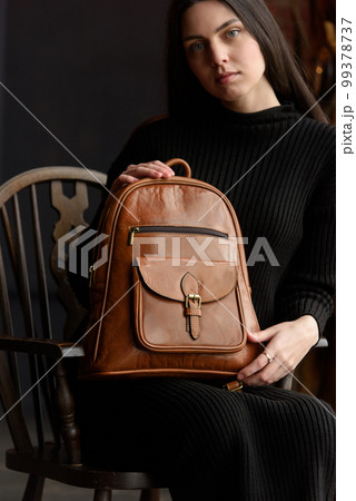 photo of a woman with a brown leather backpack with antique and retro look. indoors photo 99378737