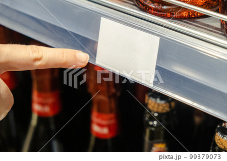 a female hand points to a price tag in a supermarket a female hand points to a price tag in a supermarket 99379073